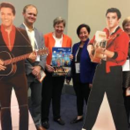 a photo of 6 people standing with 2 elvis cardboard figures