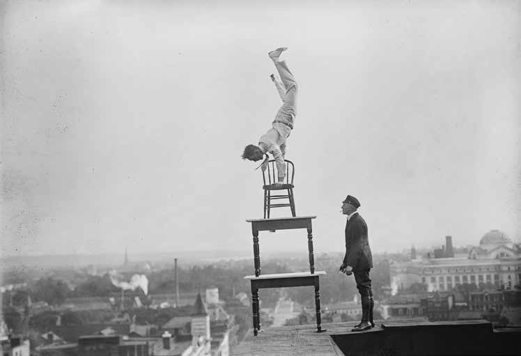 a man balancing in a handstand on top of stacked tables and chairs