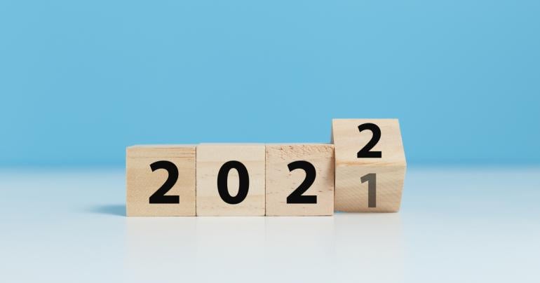 Wood blocks that spell out 2021 turning over to 2021 in front of a light blue background.