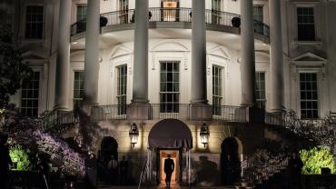 White House lit at night and man walking into the southside entryway