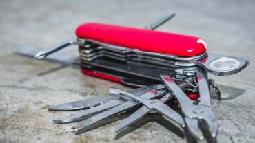 Red Swiss Army Knife that's unfolded on a stone counter