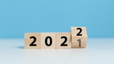 Wood blocks that spell out 2021 turning over to 2021 in front of a light blue background.