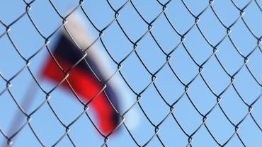 Russia flag behind chain link fence