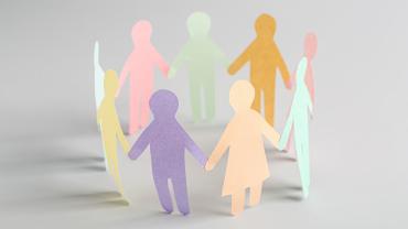 Paper cut outs of a diverse group of people holding hands in a circle. 