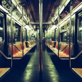 Interior of a dimly lit subway car with orange seats.