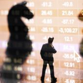 Silhouettes of two horse chess pieces and a businessman in front of stock market number on screen display
